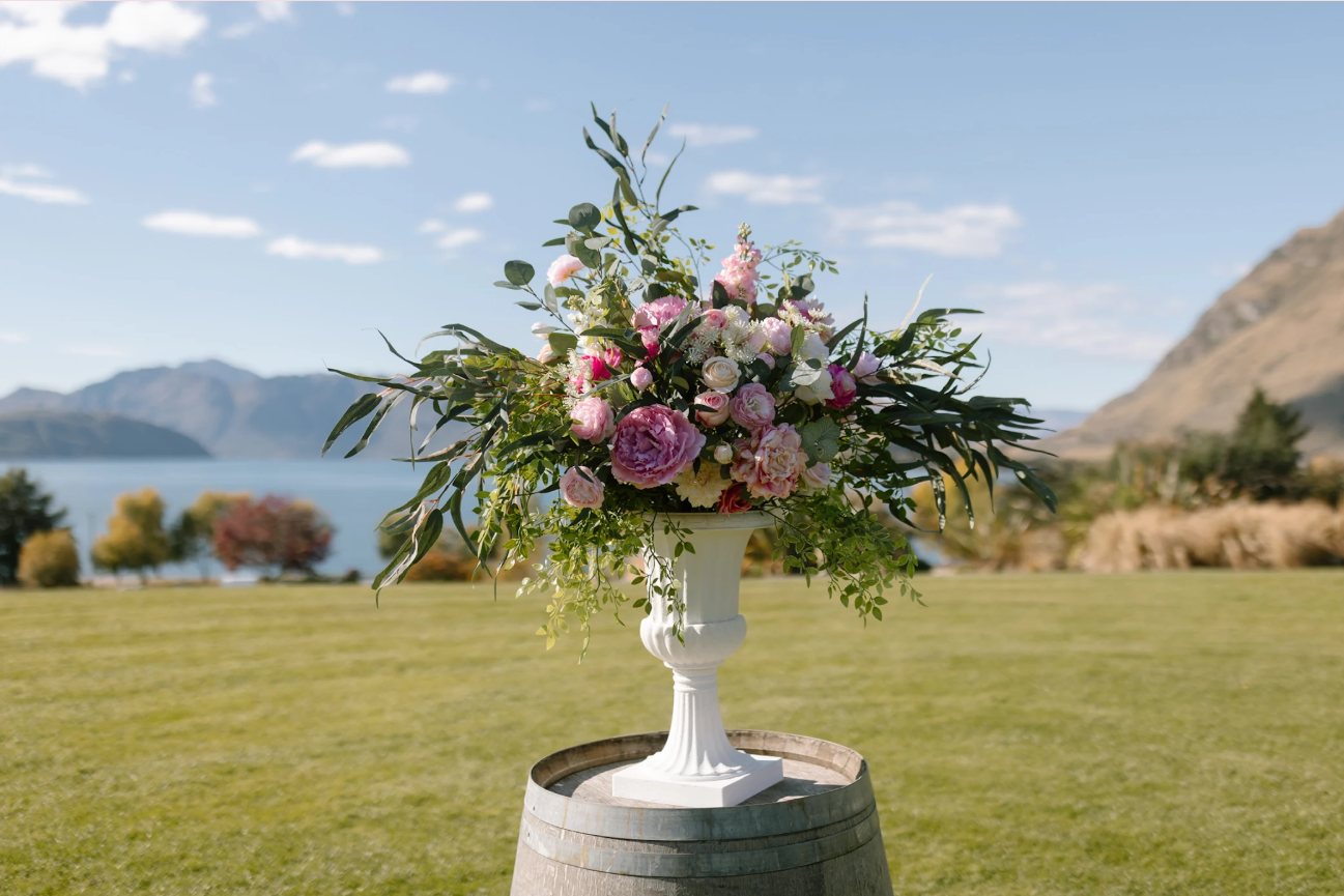 Urn arrangement on a plinth at a lakeside wedding