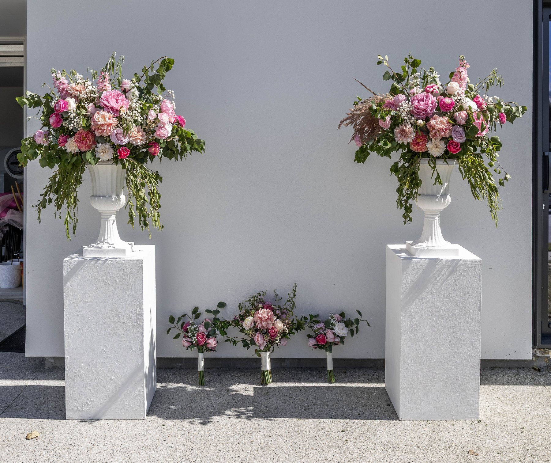 Pair of urn arrangements flanking an entrance, with bridal party bouquets